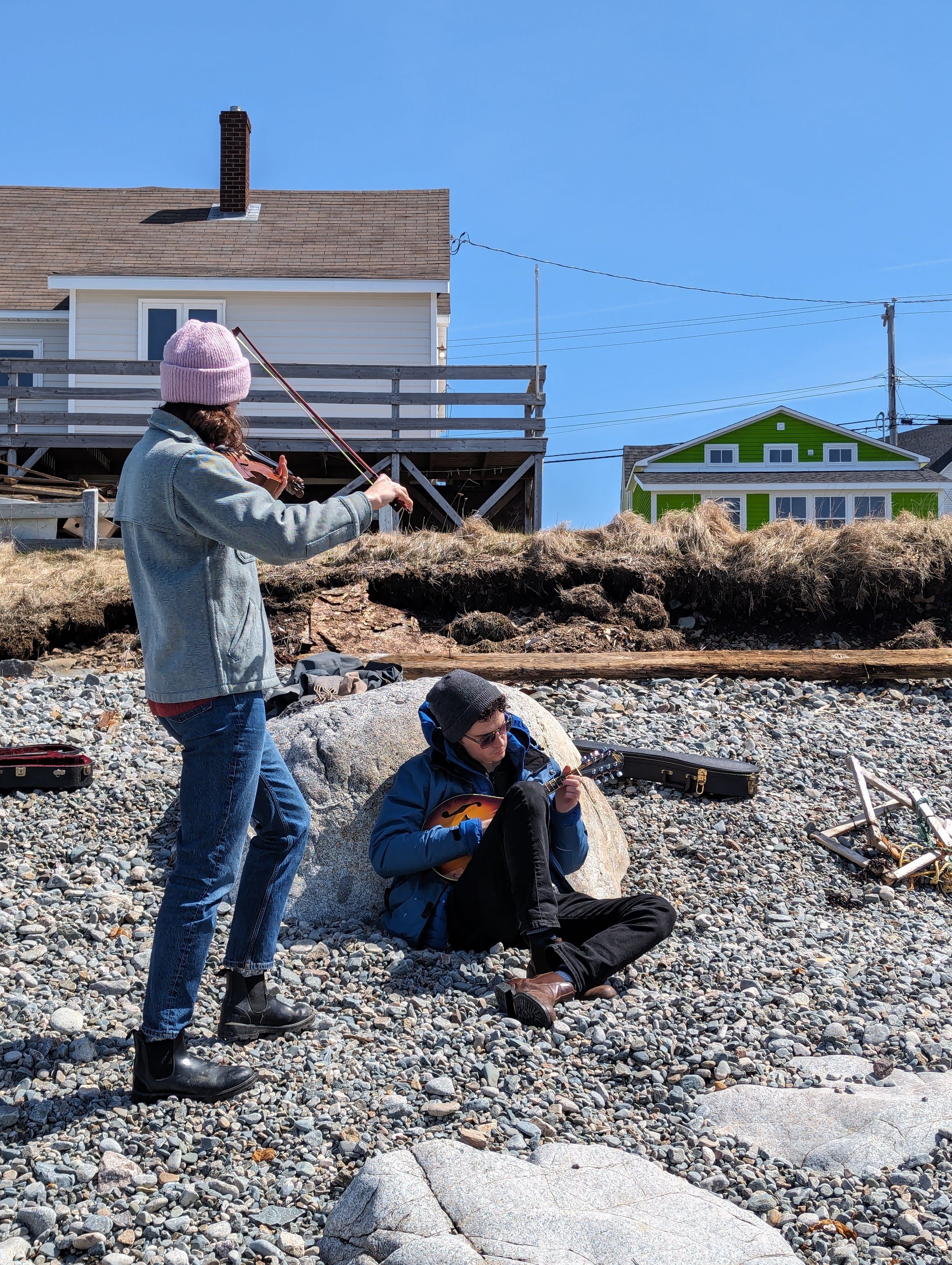 Seb and Raina playing music on a rocky beach